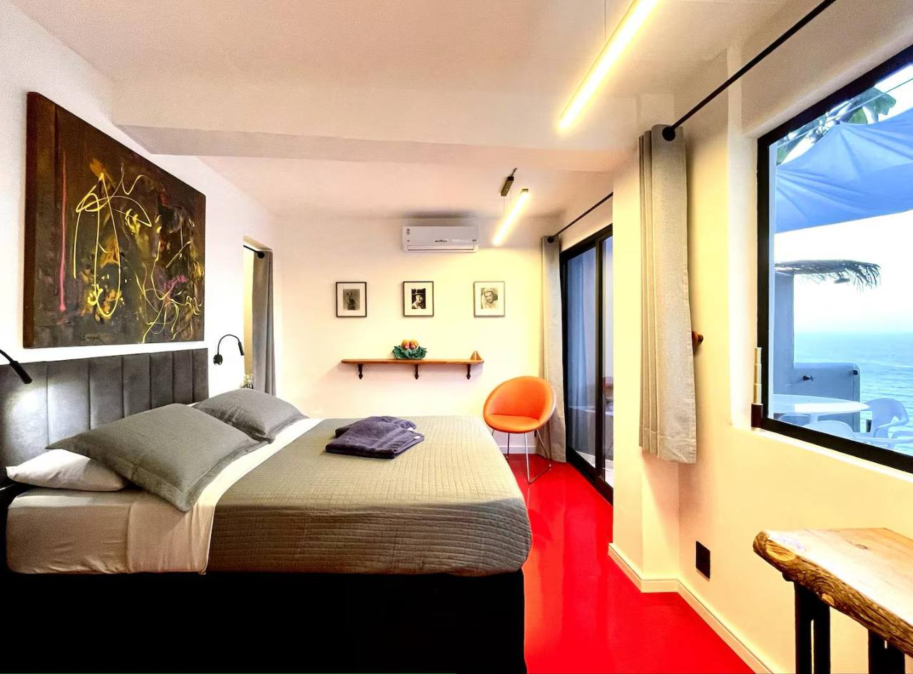 Abrir foto em tela cheia Quarto do Voo Carioca com obras de arte, luz natural e vista para o oceano.