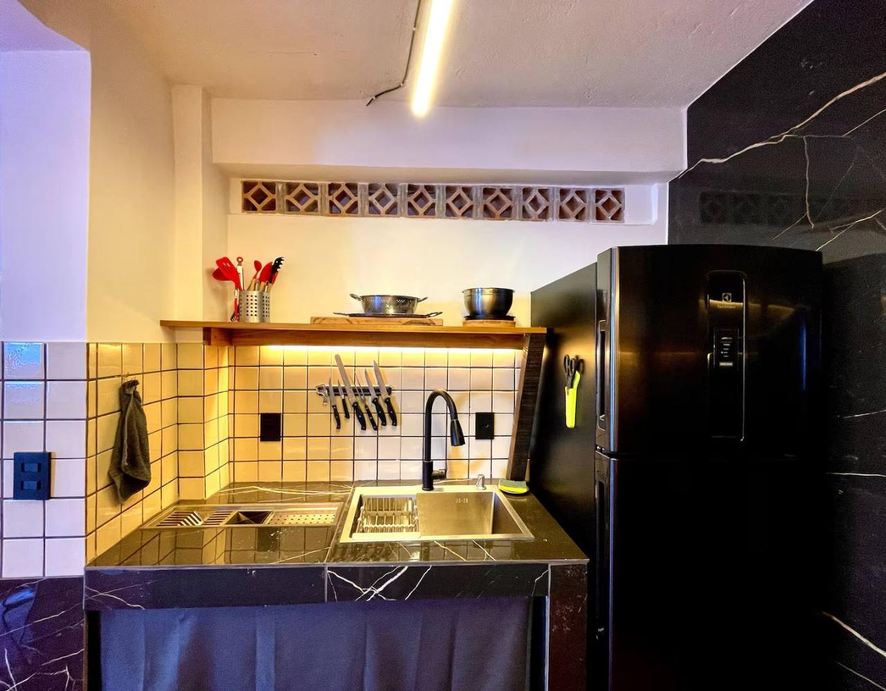 Abrir foto em tela cheia Área da pia e geladeira na cozinha totalmente equipada do apartamento.